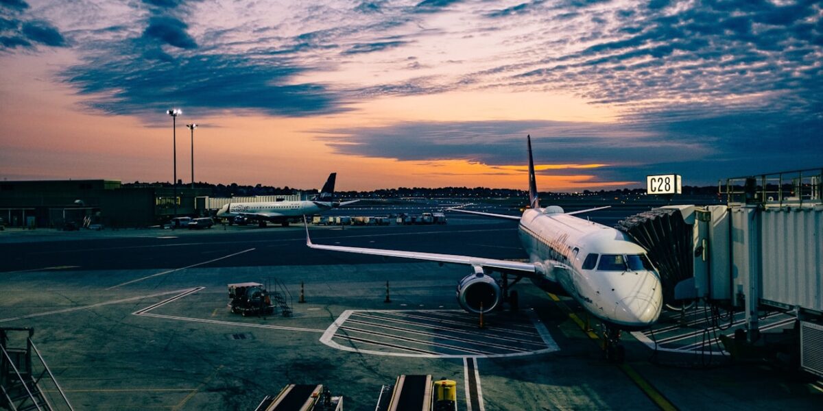 Commercial aircraft flying above clouds at sunset